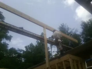 Carpenter setting a ridge beam over a new addition frame — Ice Dam Removal by Roofing Brothers in Bostic