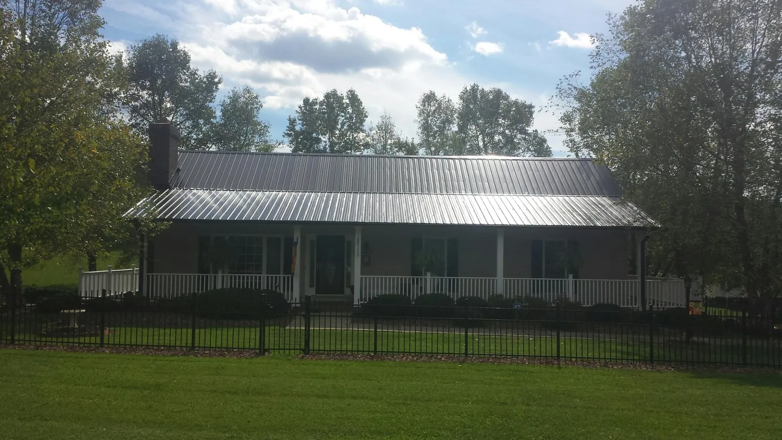Gray metal roof on a brick ranch with a full width front porch — Gutter Guard Installation work by our crew in Bostic